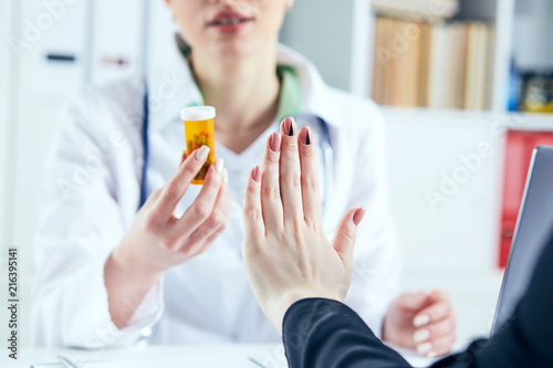 Female patient at the doctor appointment refuses to take prescribed medications, believes that they are useless and these biological drugs will only cause harm to his body. photo