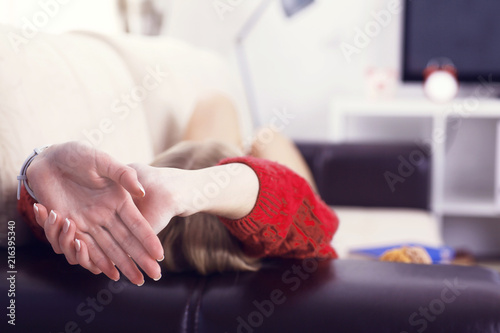 Young woman lying on comfortable couch while relaxing and stretching on sofa, enjoying resting at home.