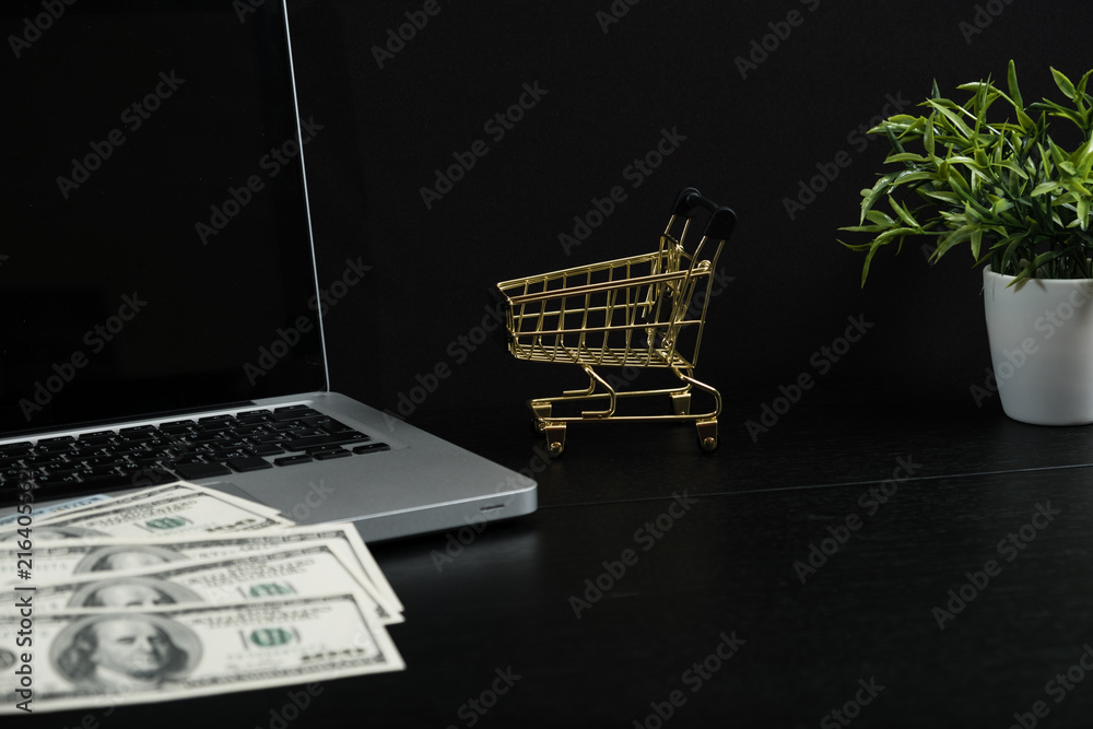 Gold cart, cash and gadgets on a black table.