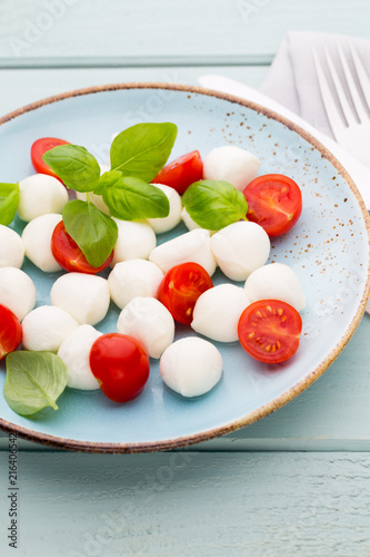 Delicious caprese salad with ripe cherry tomatoes and mini mozzarella cheese balls with fresh basil leaves.