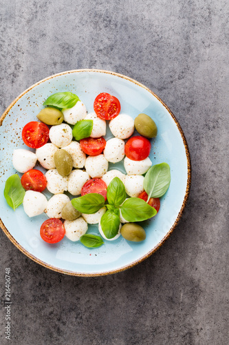 Delicious caprese salad with ripe cherry tomatoes and mini mozzarella cheese balls with fresh basil leaves.