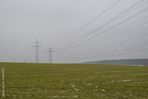 Power poles at a field in winter with some snow