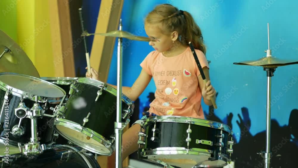 Young girl playing drums. Inept attempts to play the drums.