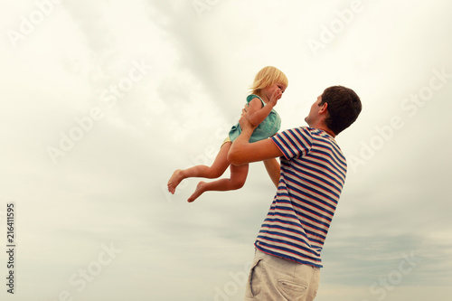 Father and daughter.Man throws up  laughing girl with blond hair.