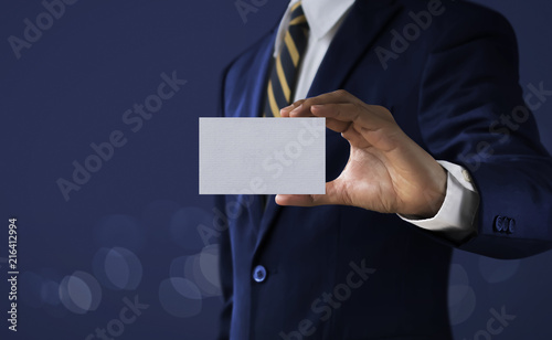 Business solution, strategy or success concept. Businessman is holding a paper card with blank space for input any text, word or message on dark tone background. photo