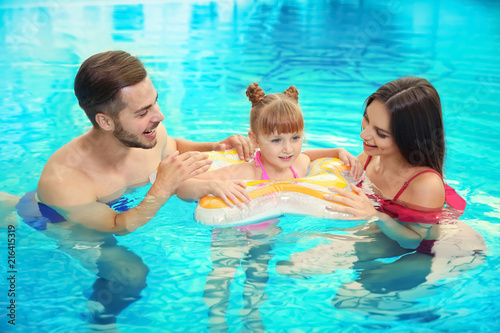 Happy family with inflatable ring in swimming pool