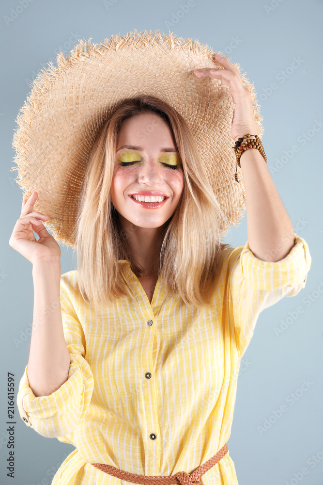 Beautiful young woman in hat on color background. Summer fashion