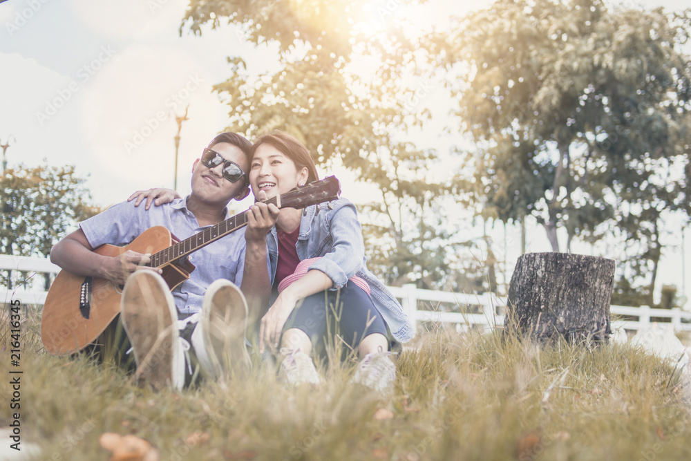 Loving couple playing guitar romantically in park