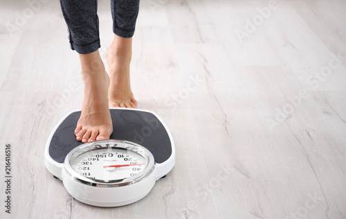 Woman measuring her weight using scales on floor photo