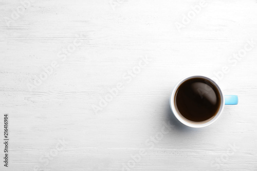 Ceramic cup with hot aromatic coffee on wooden background, top view