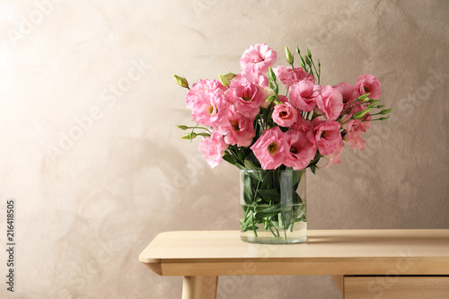 Fototapeta Naklejka Na Ścianę i Meble -  Vase with beautiful Eustoma flowers on table against color background