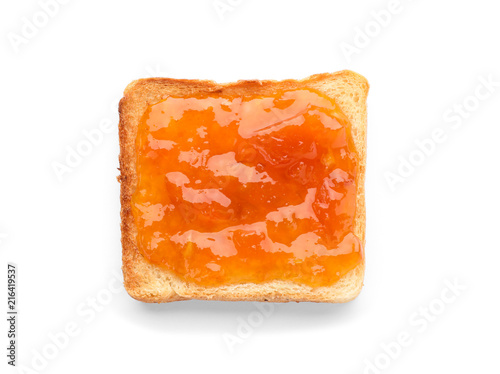 Bread with tasty apricot jam on white background, top view