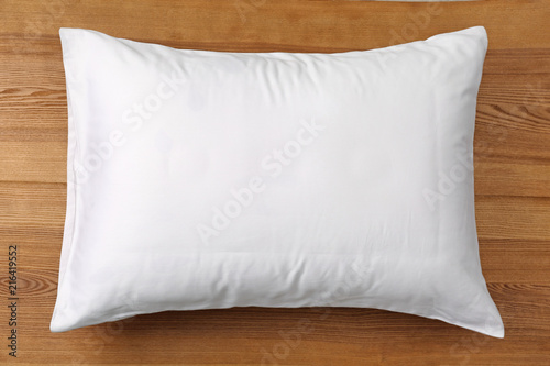 Soft bed pillow on wooden background, top view