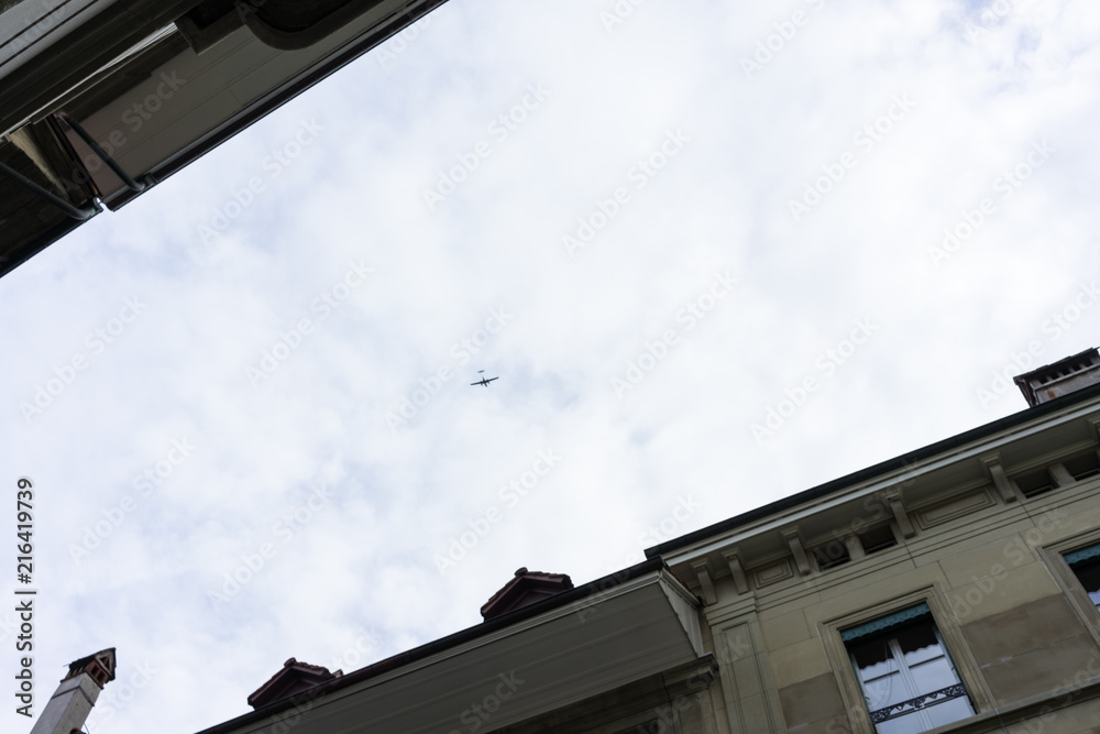 airplaine flying over buildings with white clouds airplaine flying over buildings with white clouds