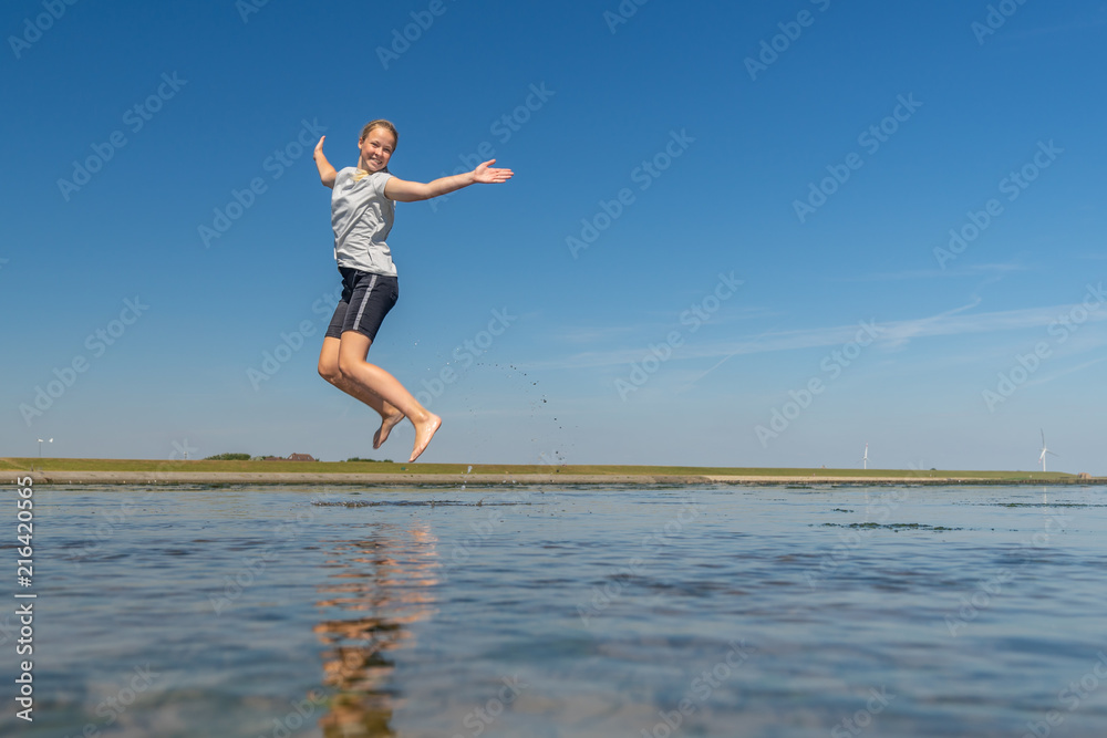 junges Mädchen springt im Wattenmeer der Nordsee vor Freude in die Luft
