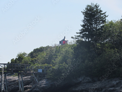 View of Hendricks Head Lighthouse in Southport, Maine behind trees and plants in the summer  photo