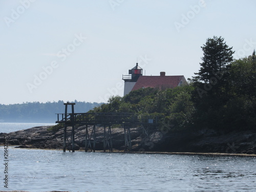 View of Hendricks Head Lighthouse in Southport, Maine behind trees and plants in the summer  photo