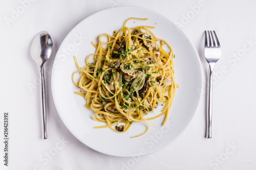 Top view of Oyster spaghetti served in white plate on white tablecloth.