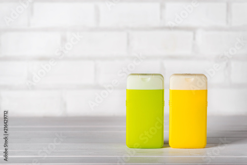 Two closed plastic shampoo and conditioner containers, green and yellow, on white background. Copy space