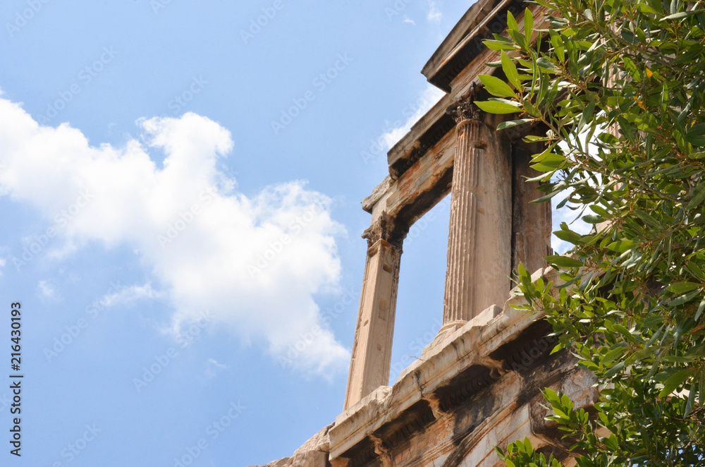 Blue sky and clouds and old ancient columns in the back of branches