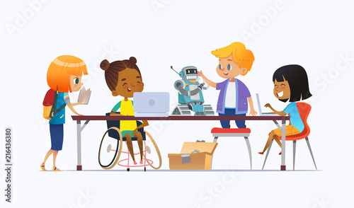 Disabled African American girl in wheelchair and other children standing around desk with laptops and robot and working on school project for programming lesson. Concept of inclusion at school.