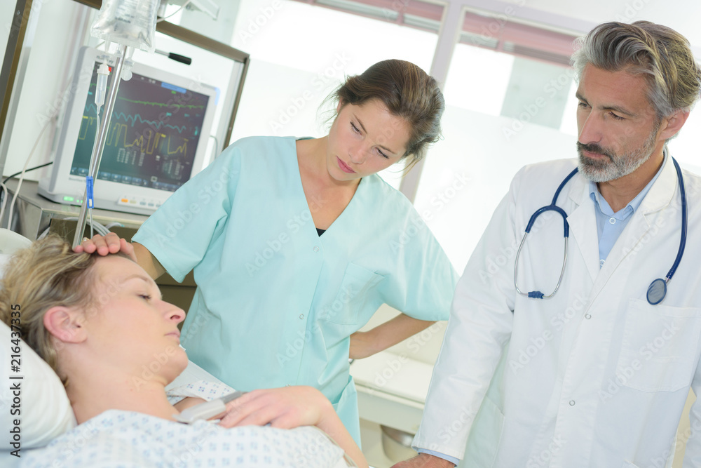 Obraz premium patient sleeping on the bed while doctors checking on her