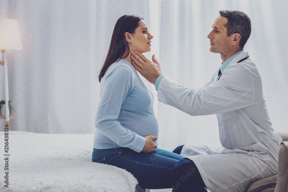 Visiting consultation. Attentive medical worker sitting opposite his patient and examining throat Visiting consultation. Attentive medical worker sitting opposite his patient and examining throat