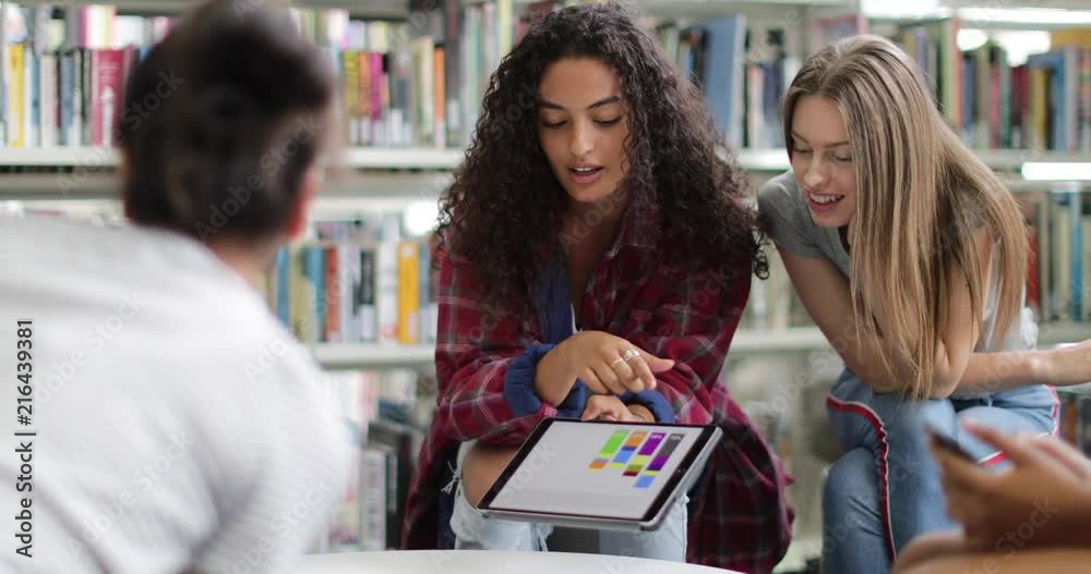 High school students studying together in a library with a digital tablet High school students studying together in a library with a digital tablet