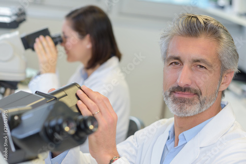mature male researcher using microscope in medical laboratory