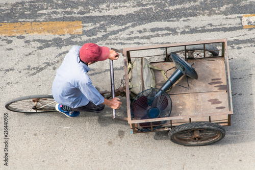 A man on a tricycle carries a fan on a cart, Ho Chi Minh city, Vietnam. photo