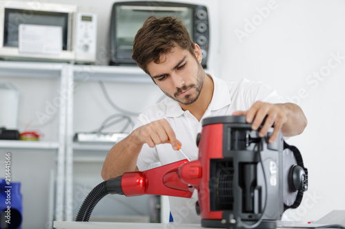 handsome young repairman fixing vacuum cleaner