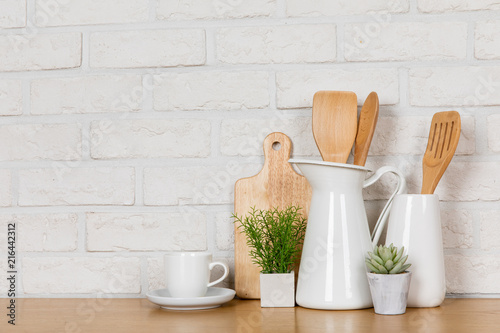 There are various cookers on the table, background made of bricks painted white color only. It feels a homelike atmosphere looking a tidy table in the kitchen.