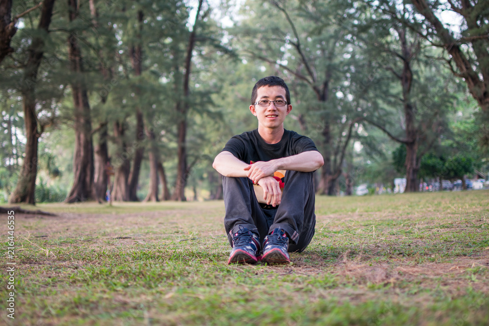 Man sitting on the ground with big pine tree in background Man sitting on the ground with big pine tree in background