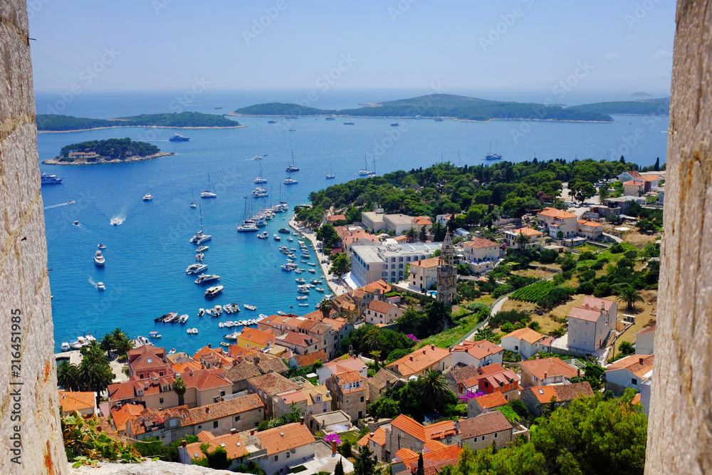 Hvar town harbor from the Spanish Fortress framed by a stone window