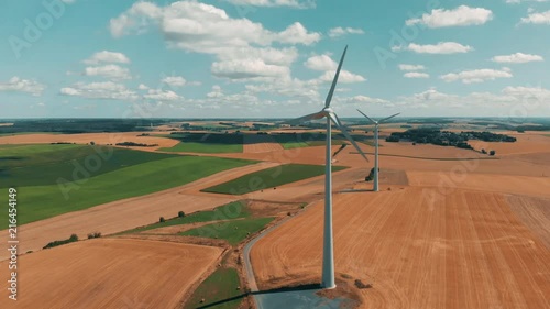 Aerial view of wind turbines and wind gernerators in motion on a summers day over wheat crops with with large open sky