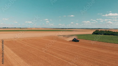 Aerial drone view of red tracor working in wheat field. Agriculture and environment in European Union. photo