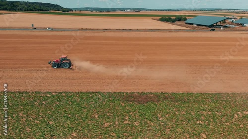 Aerial drone view of red tracor working in wheat field. Agriculture and environment in European Union. photo