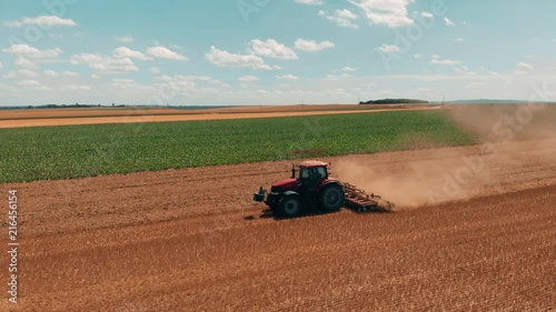 Aerial drone view of red tracor working in wheat field. Agriculture and environment in European Union. photo