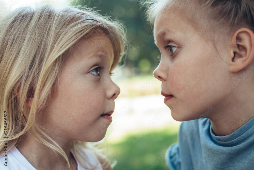 Profile of small girls standing and looking at each other with eyes wide open. They are playing games outside with joy Profile of small girls standing and looking at each other with eyes wide open. They are playing games outside with joy