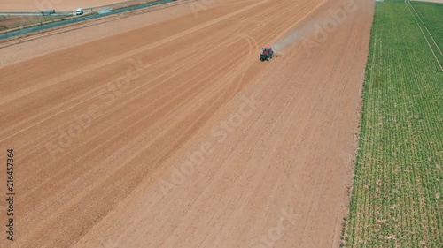 Aerial drone view of red tracor working in wheat field. Agriculture and environment in European Union. photo