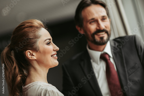 Side view beaming lady talking with glad unshaven man during rest at job. Pleased partners during communication concept