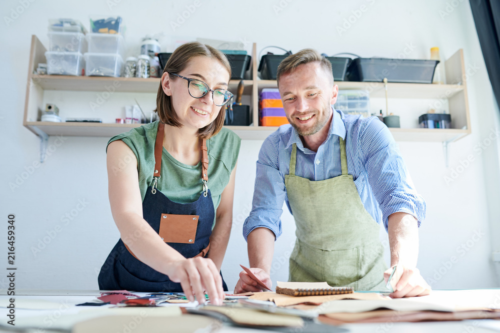 Obraz premium Two clothiers communicating while working together at the table in workshop