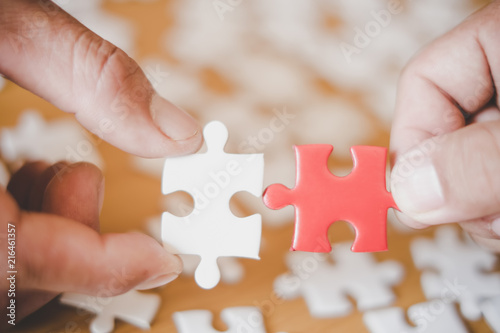 Hands of business people hold paper jigsaw puzzle and solving puzzle together,Business team assembling Jigsaw puzzle,Business group wanting to put pieces of puzzle together.