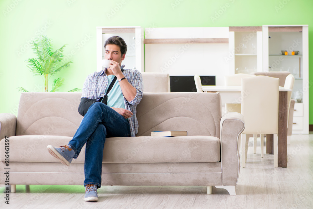 Young student man with hand injury sitting on the sofa Young student man with hand injury sitting on the sofa