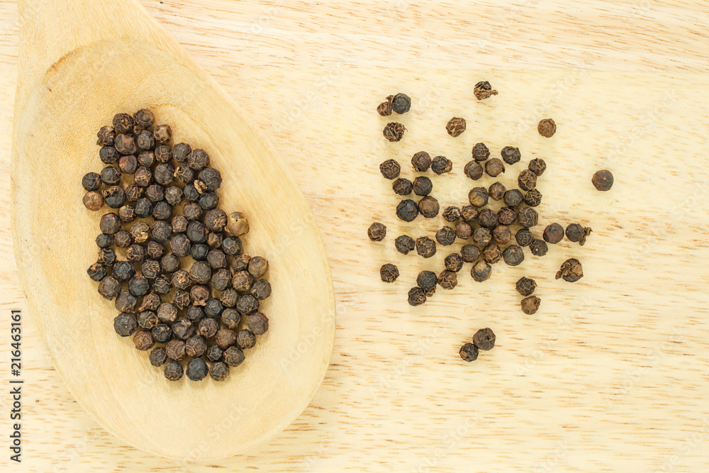 peppercorns in spoon heap on wooden table. peppercorns in spoon heap on wooden table.
