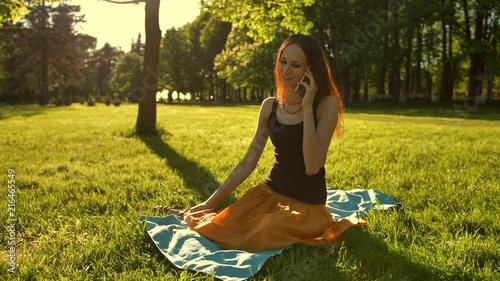 Front view of a woman sitting towards camera talking during a selfphone calling her friend in the park photo