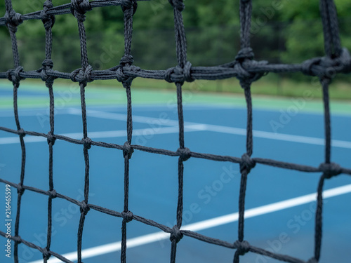 Zoomed view of tennis court net mesh with blurry courts in background 