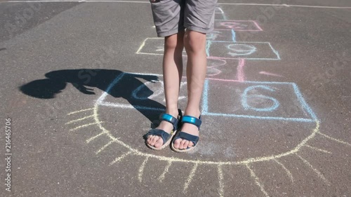 Boy jumps playing hopscotch in the street. Close-up legs. photo