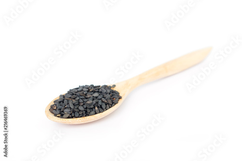 Heap of black sesame on wooden spoon on white background.