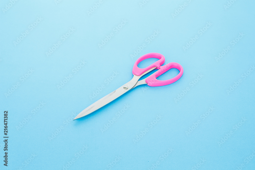 pink scissors cutting on blue background pink scissors cutting on blue background